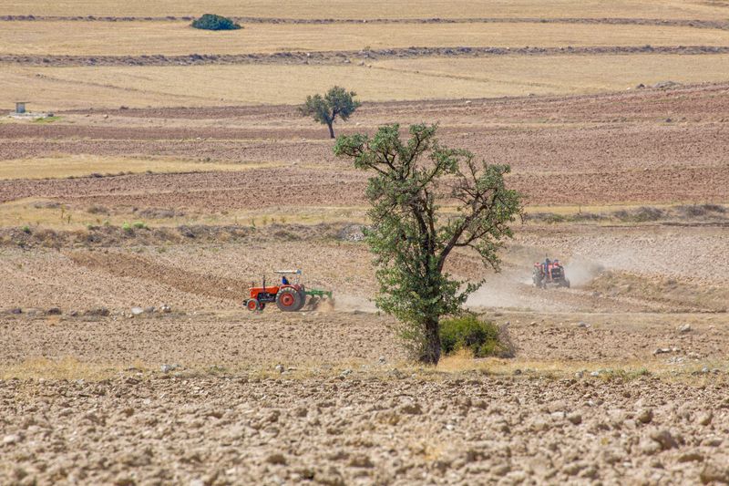 Suha zemlja i traktor u polju pod jakim suncem