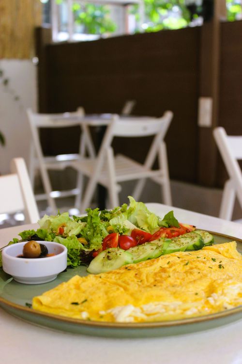 Free Delicious omelette with a fresh salad and olives served in a cozy cafe setting. Stock Photo