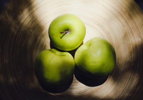 Free Close-up of fresh green apples in a wooden tray with natural lighting, perfect for healthy lifestyle themes. Stock Photo