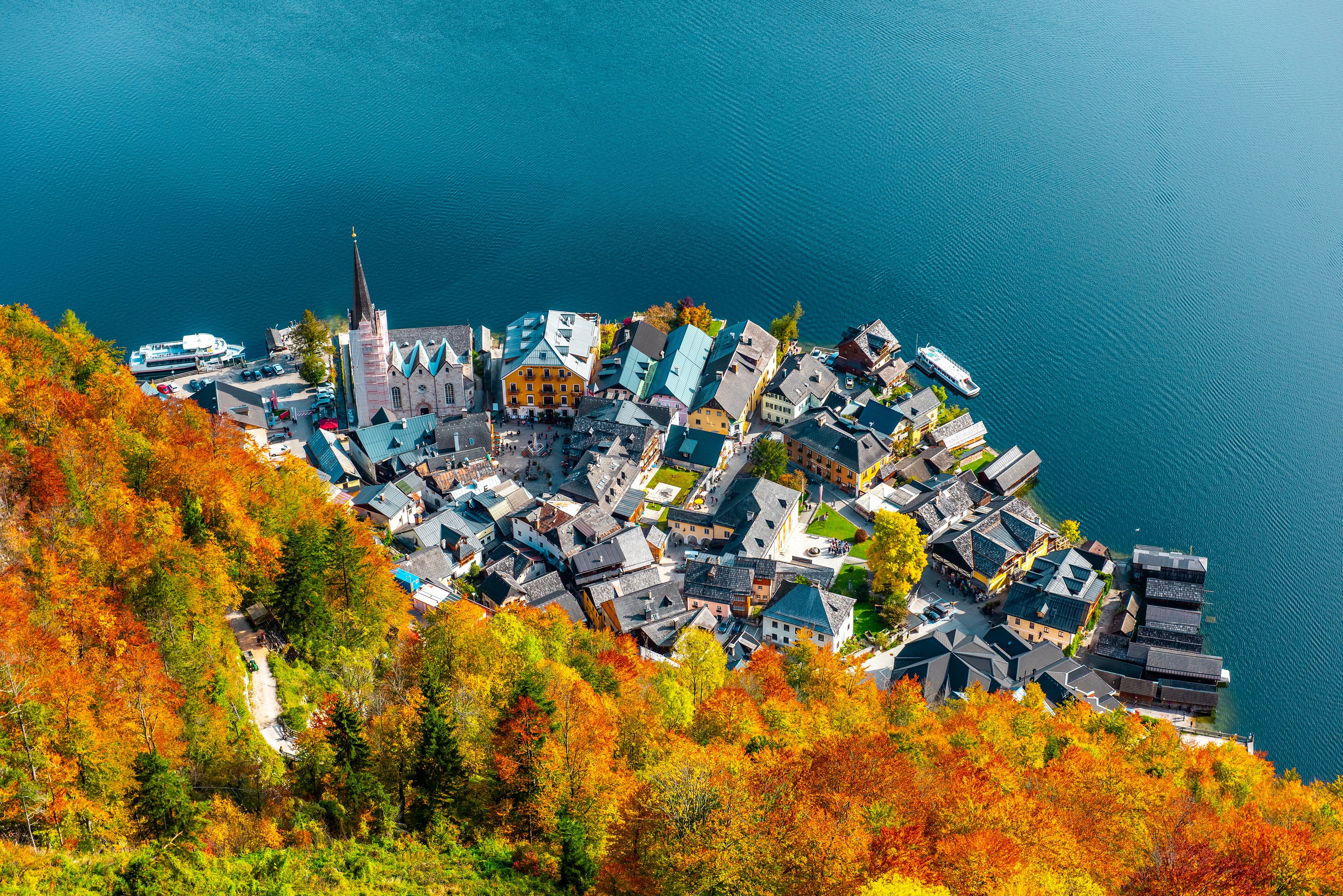 Stunning aerial view of charming Hallstatt, Austria surrounded by vibrant fall colors by the serene lake.