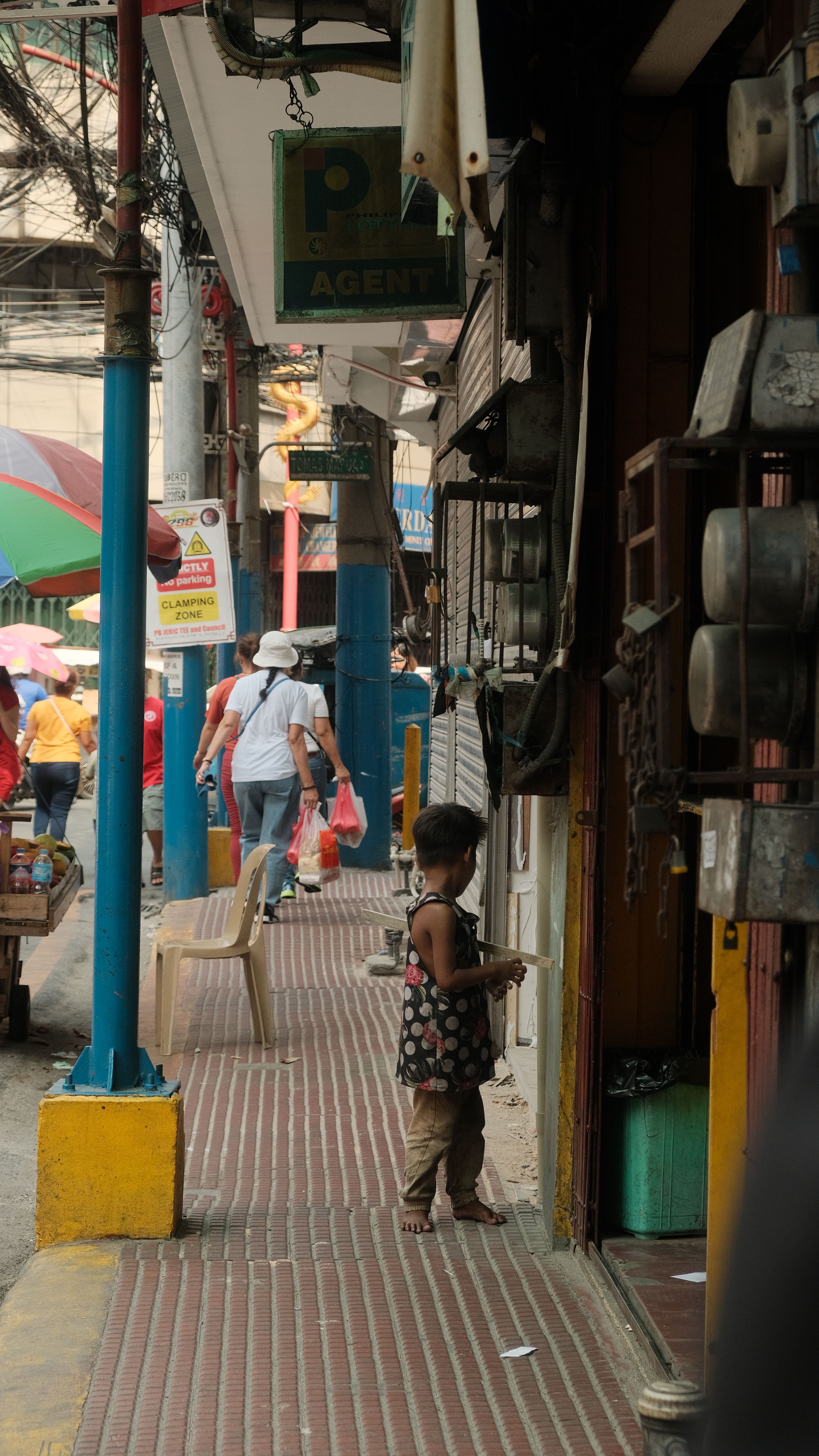 Child on a bustling street in Manila's Chinatown, vibrant city life captured.