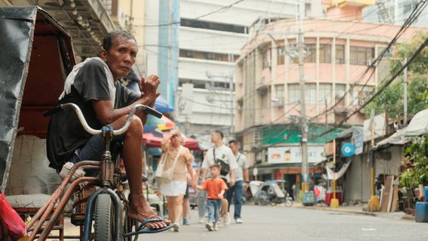 Candid scene capturing a man on a bicycle in Manila's busy city street, highlighting urban daily life.