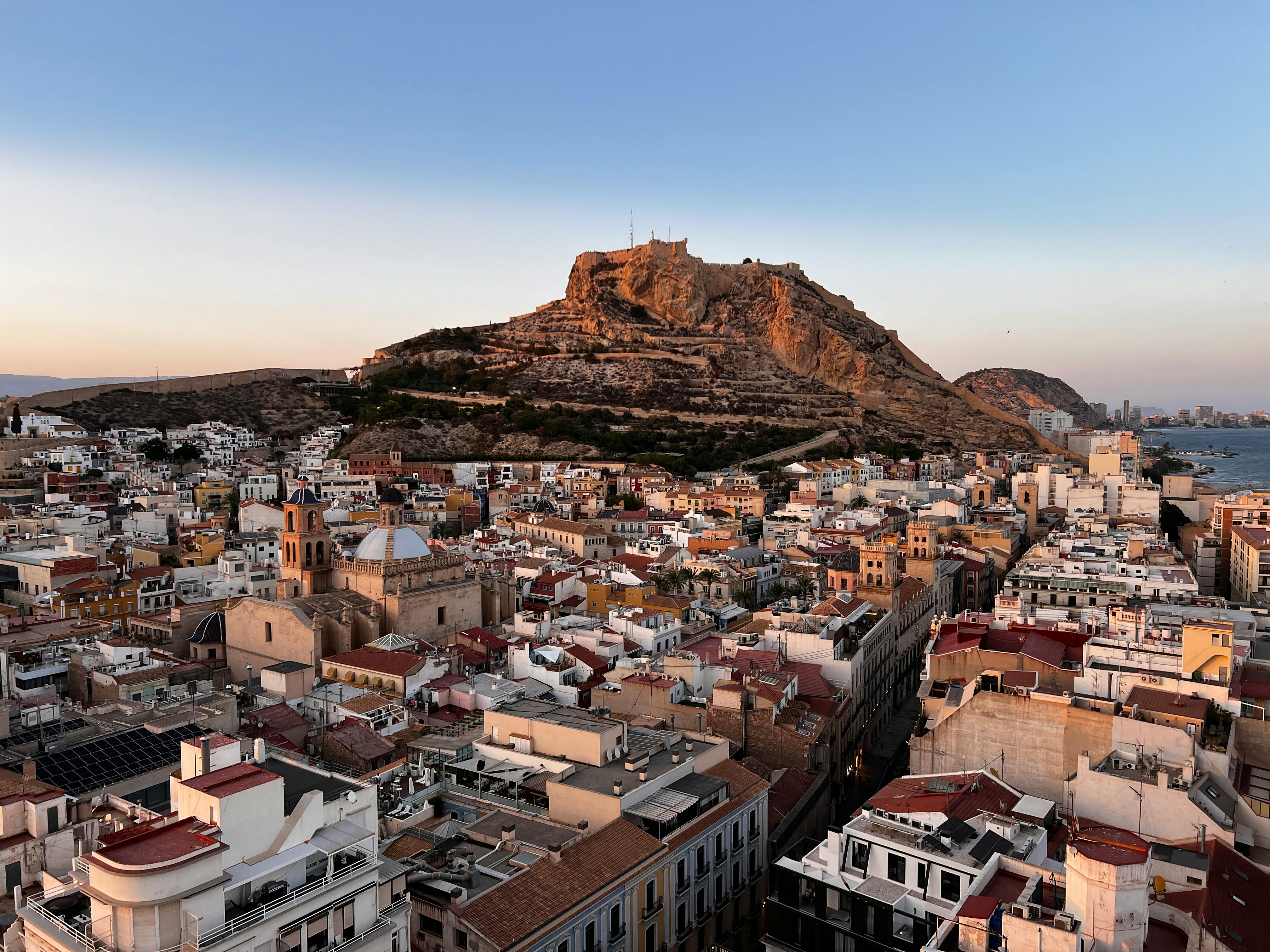 A panoramic view of Alicante with the iconic Santa Bárbara Castle and the Mediterranean Sea.