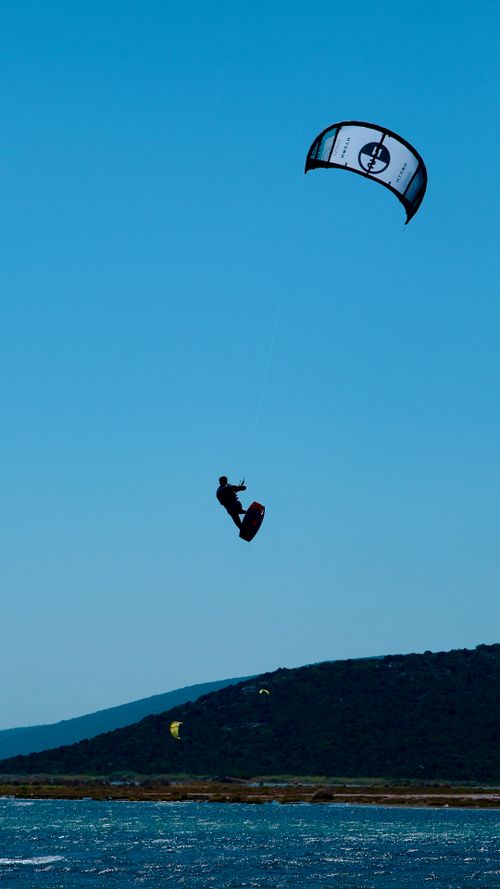 Free A kitesurfer soars above the waters of Gülbahçe, İzmir, capturing the thrill of summer adventure. Stock Photo