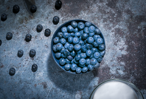 Free Top-down shot of fresh blueberries in a bowl on rustic surface with dramatic lighting. Stock Photo