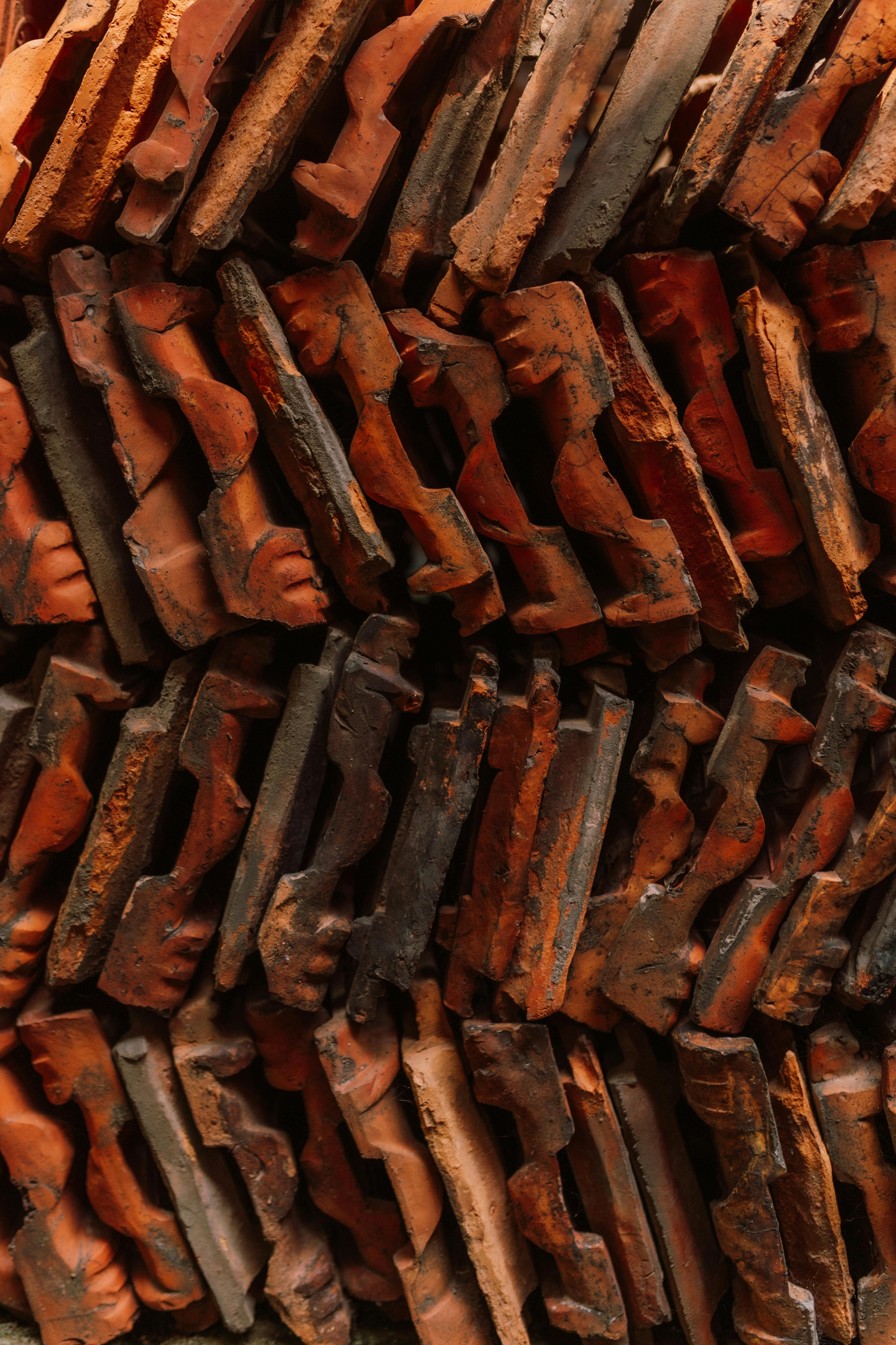 Detailed view of stacked rustic red clay roof tiles with rich textures and patterns.