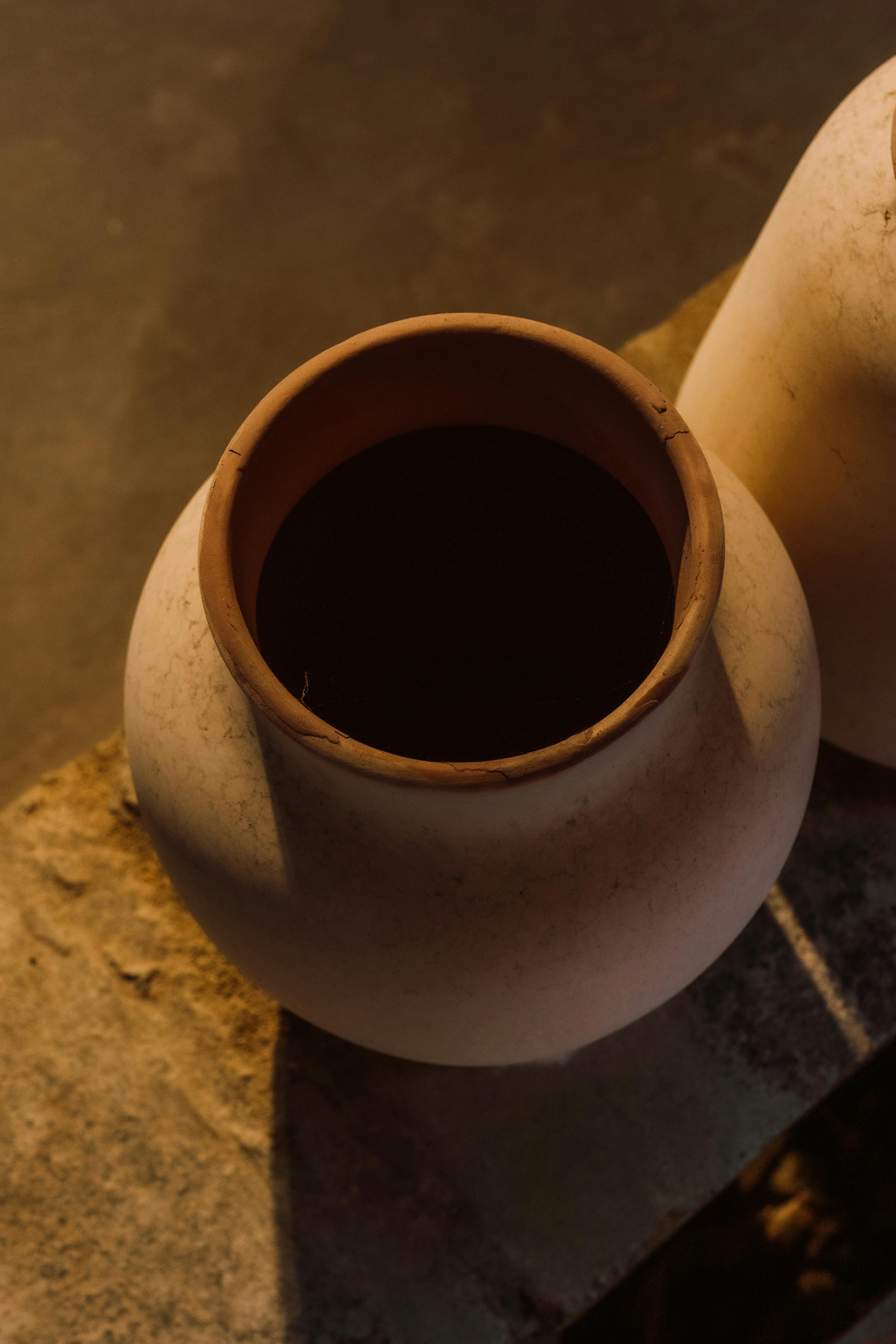 two clay pots sitting on a table with a brown background