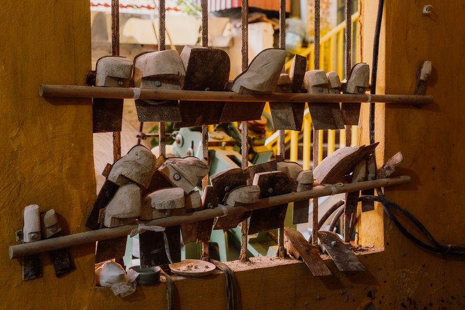 A collection of vintage industrial tools displayed on a wooden rack in an artisan workshop.