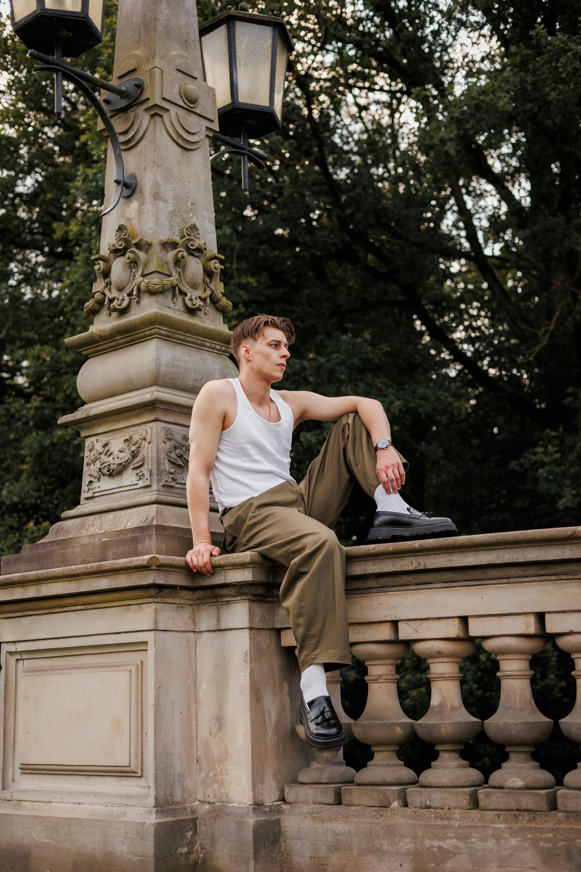 man in tank top sitting on wall