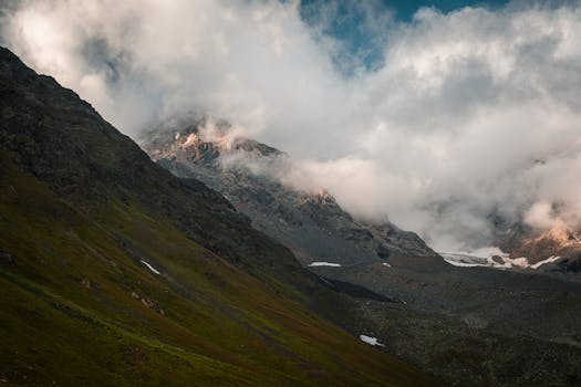 Breathtaking view of a mountain range shrouded in clouds, showcasing snow patches and rocky peaks.
