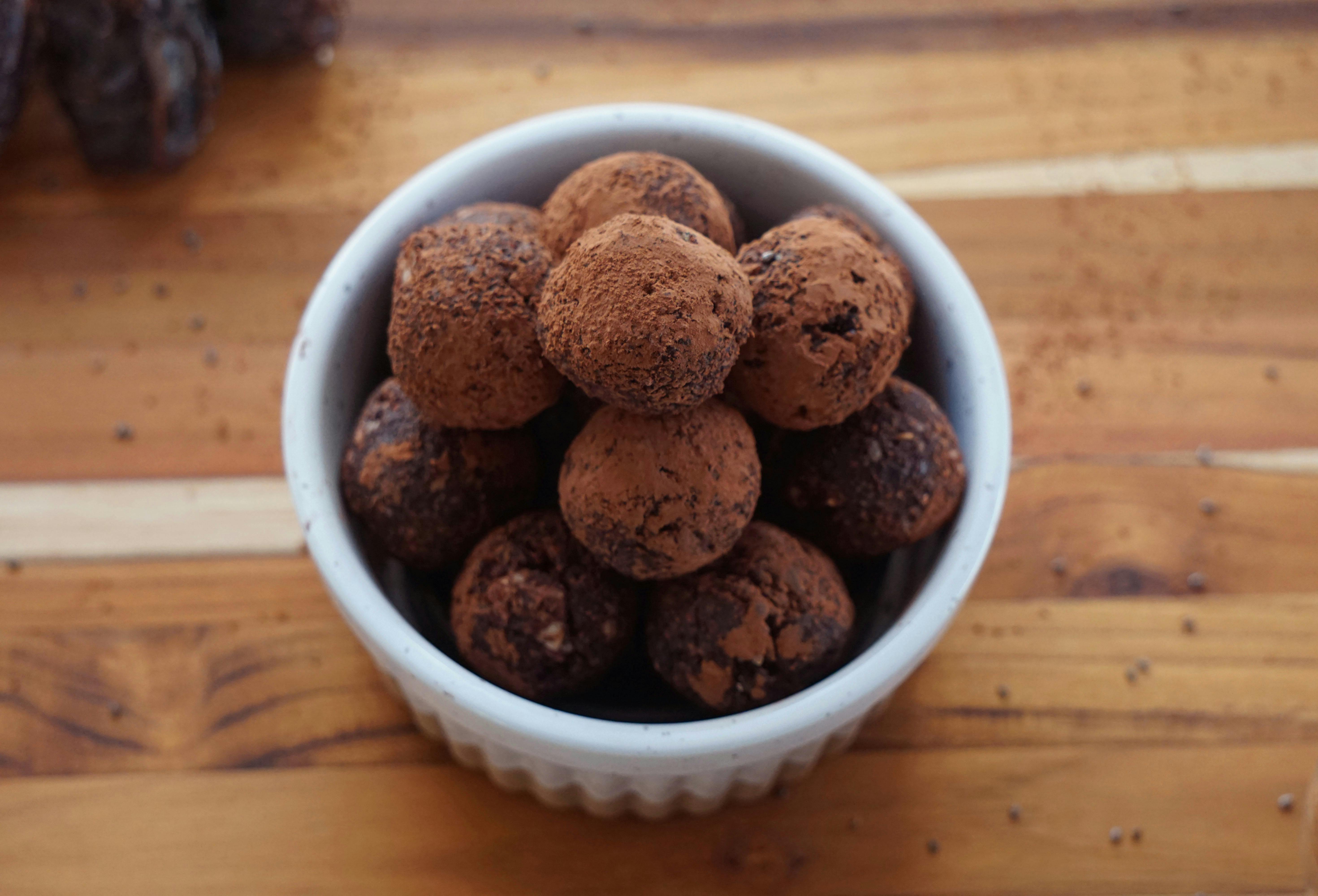 a bowl of chocolate truffles on a wooden table