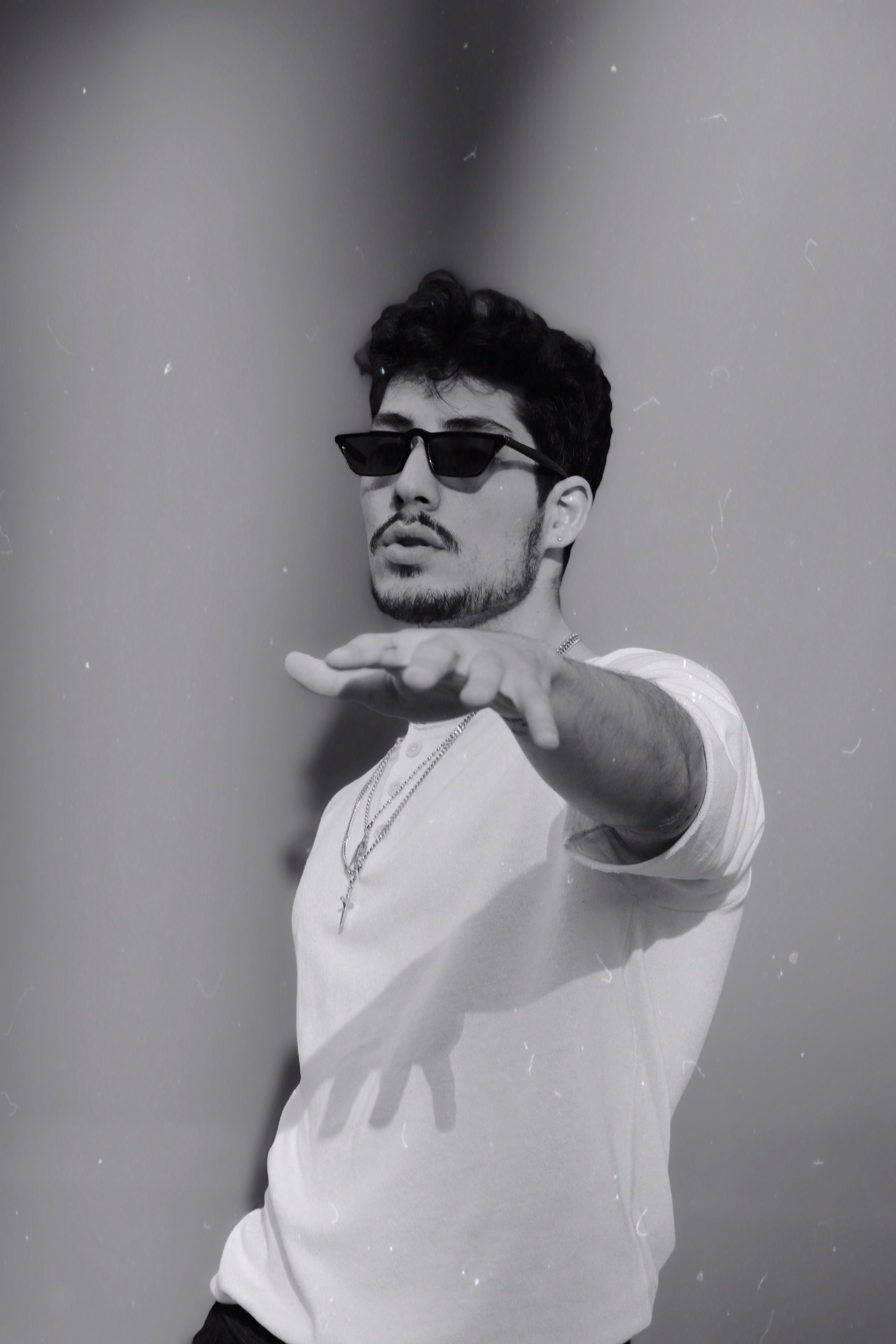 Monochrome portrait of a fashionable man in sunglasses reaching forward, set in İstanbul.