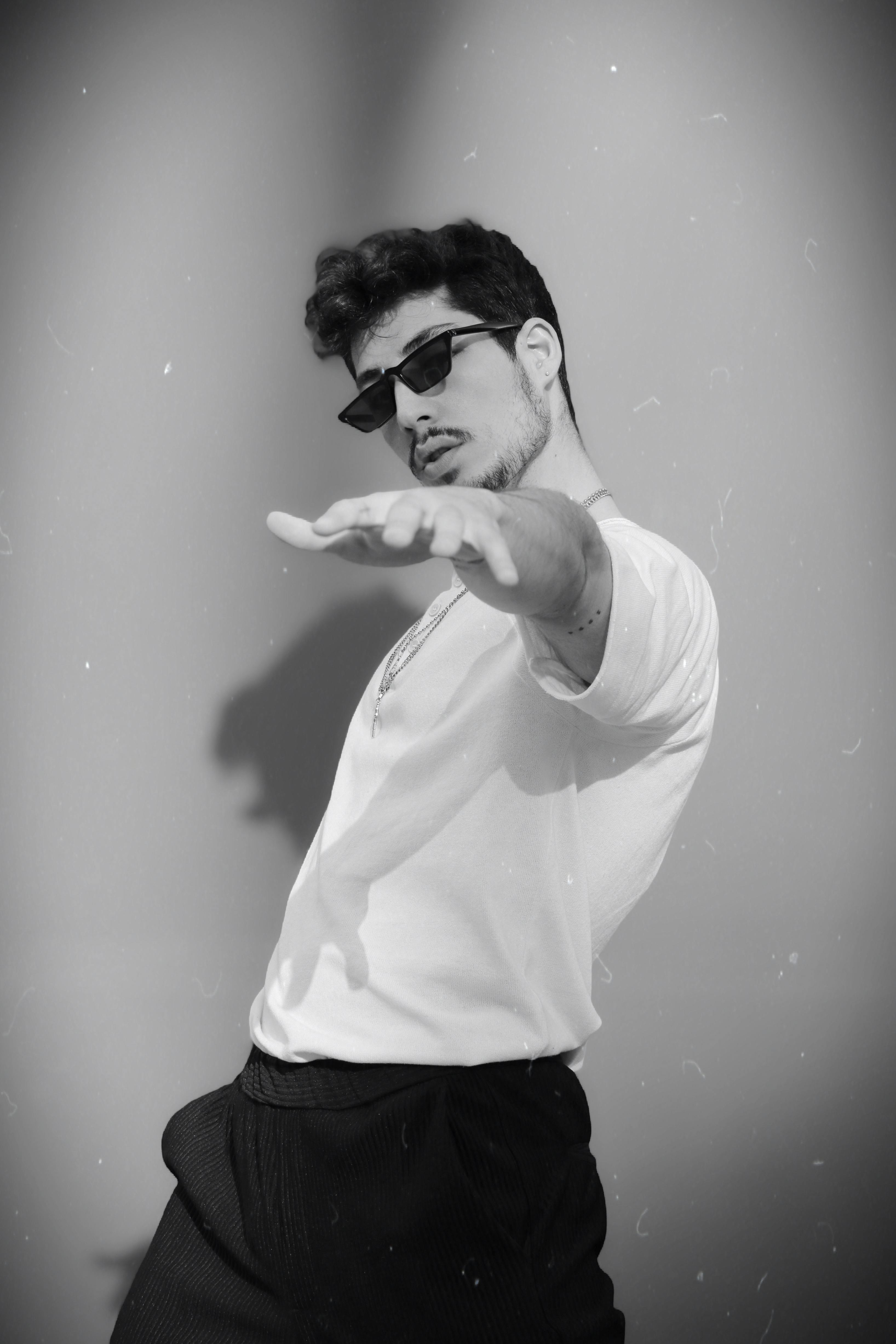 a man in sunglasses and a white shirt is pointing at something