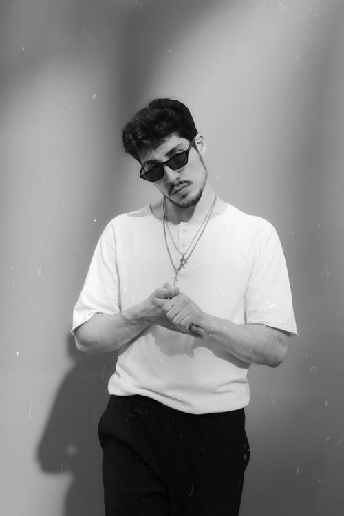 Free Black and white portrait of a stylish young man wearing sunglasses and a casual outfit. Stock Photo
