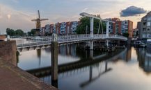 A bridge over a canal with a windmill in the background