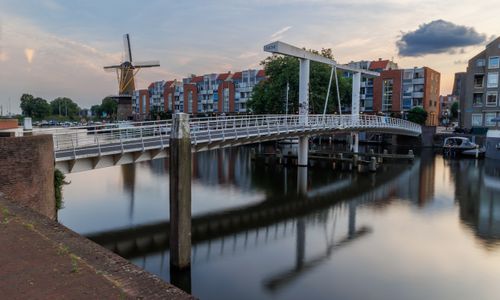 Free Tranquil sunset view of a drawbridge and windmill by Rotterdam canal. Stock Photo