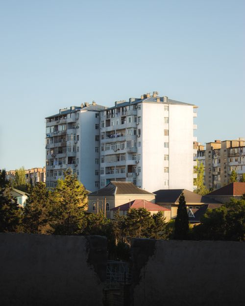 Free Modern multi-story apartment buildings in a leafy urban setting, under clear skies. Stock Photo