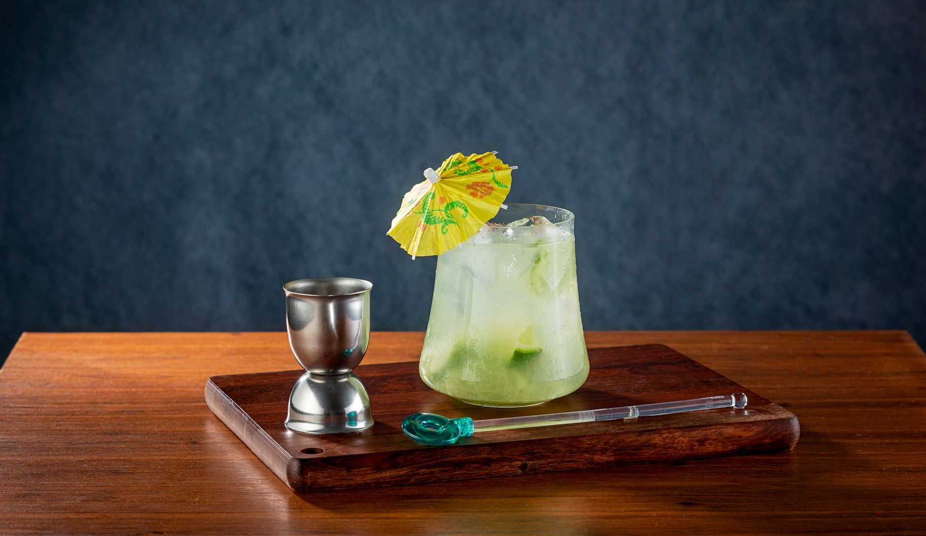 Several colorful cocktail sticks displayed next to a glass of mixed drink with ice