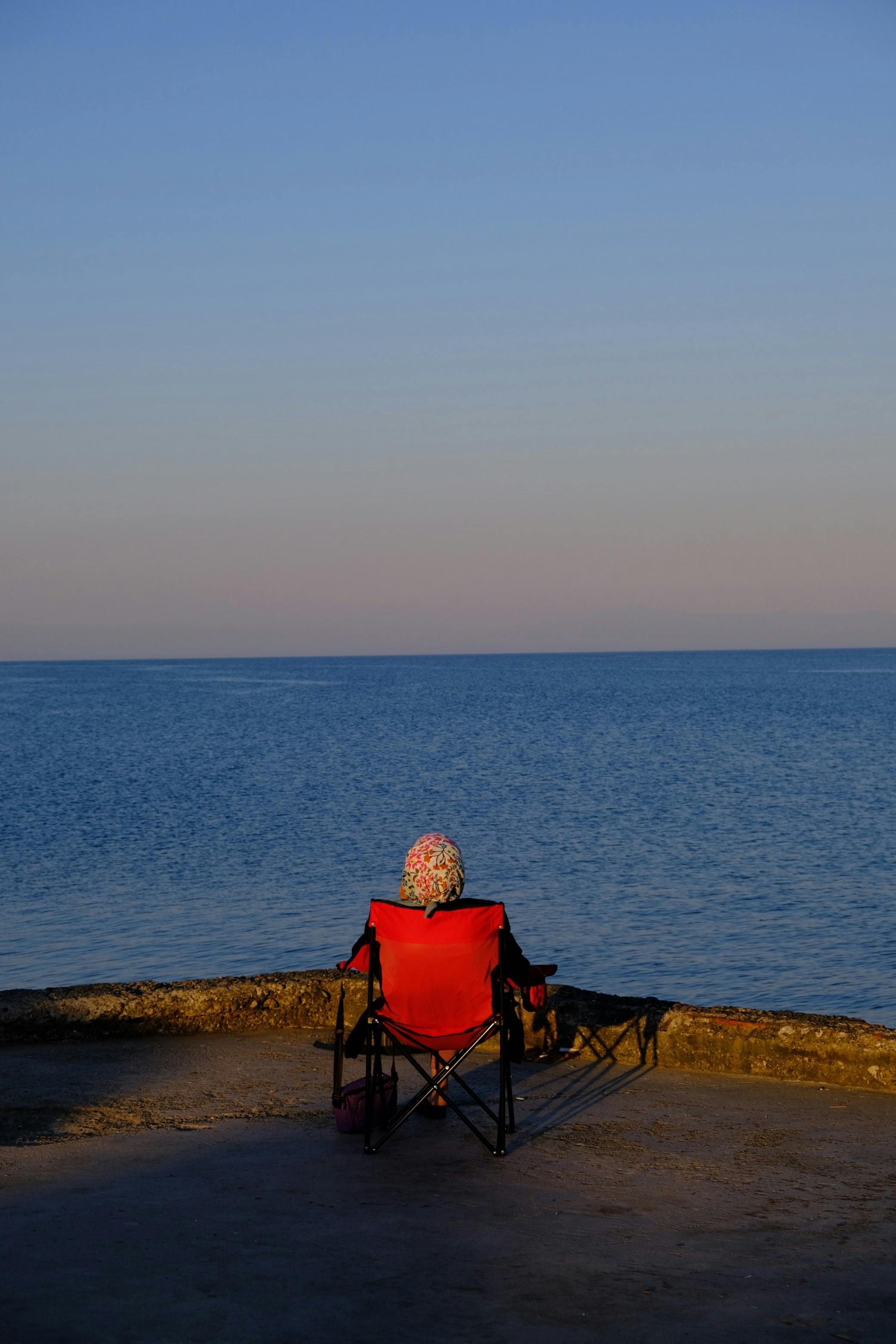 A person relaxes by the seaside at sunset in Karataş, Türkiye, enjoying solitude and calm.