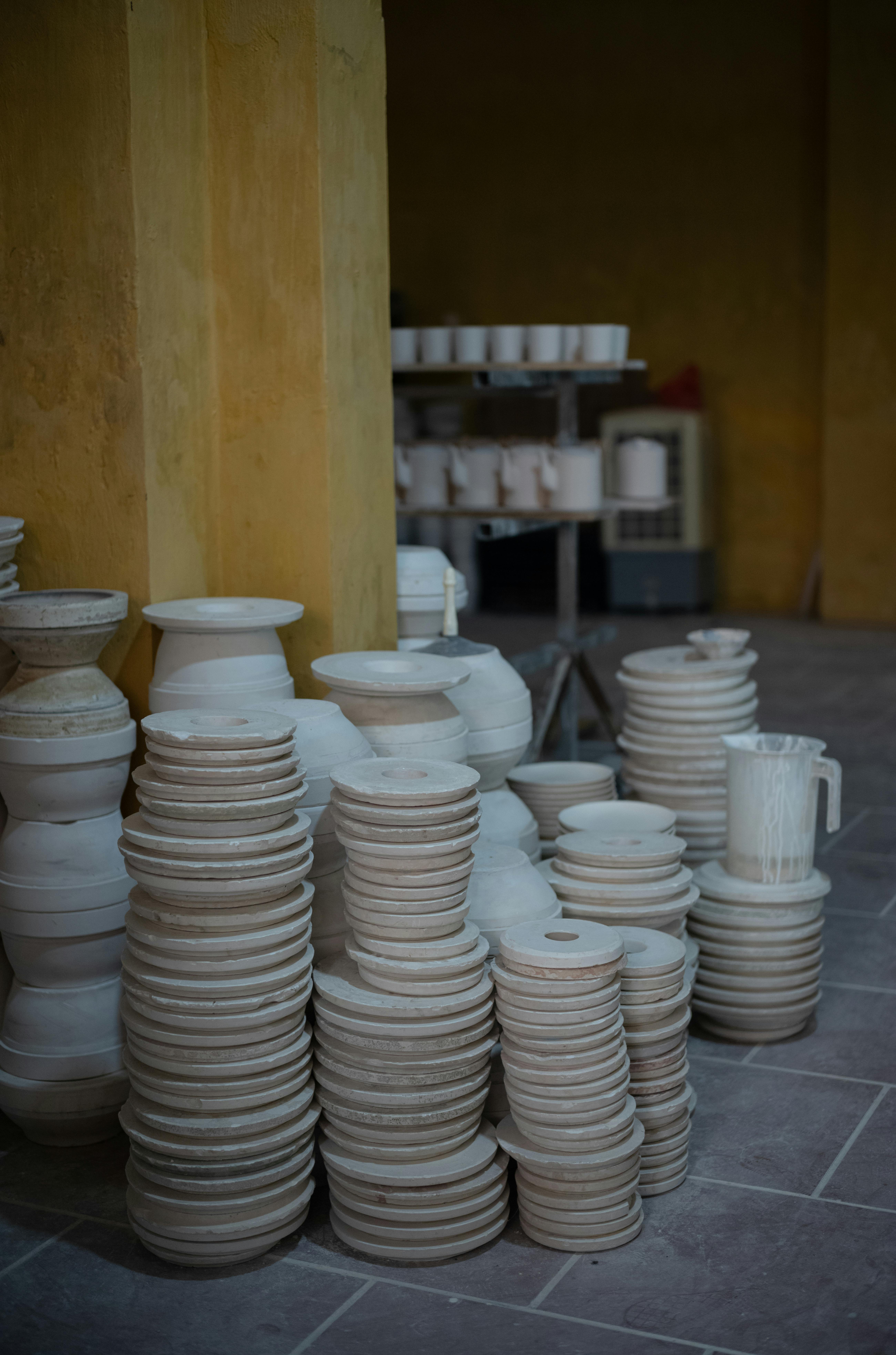 Stacks of ceramic pottery arranged in an indoor workshop setting.