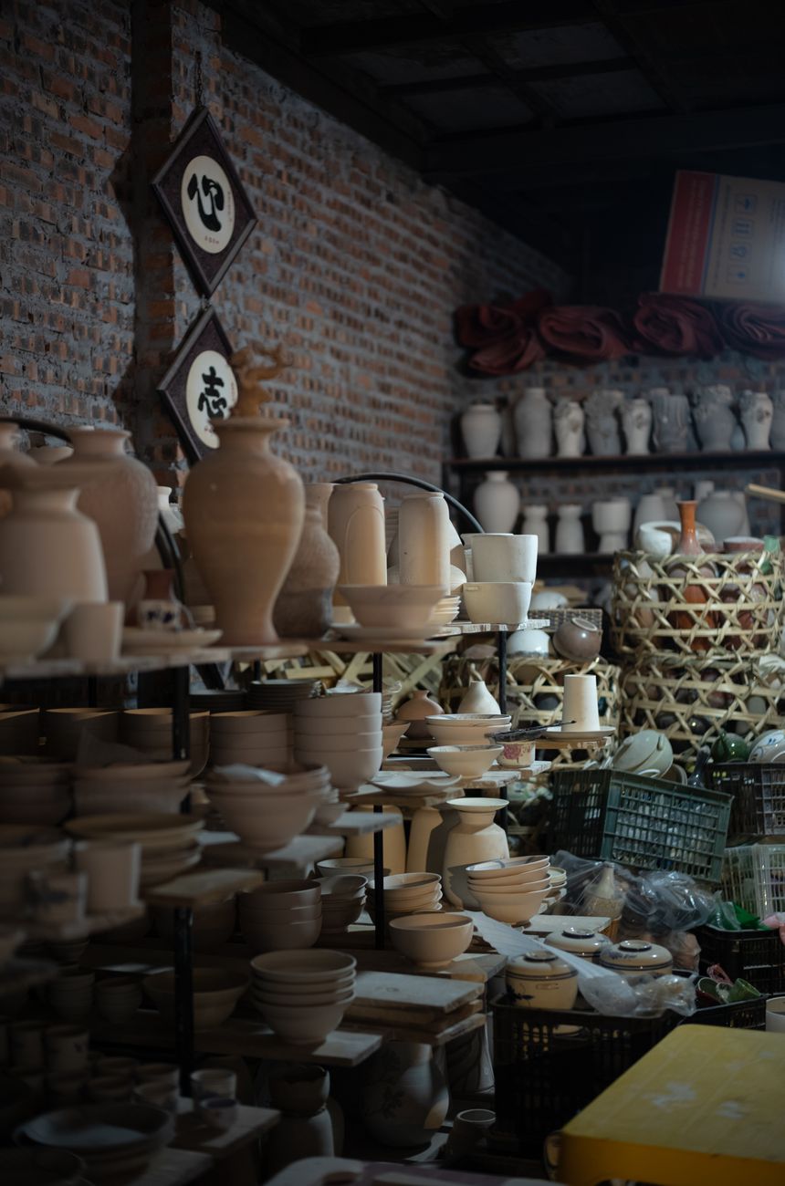 Explore shelves filled with handmade ceramics in an artisan workshop's cozy interior.