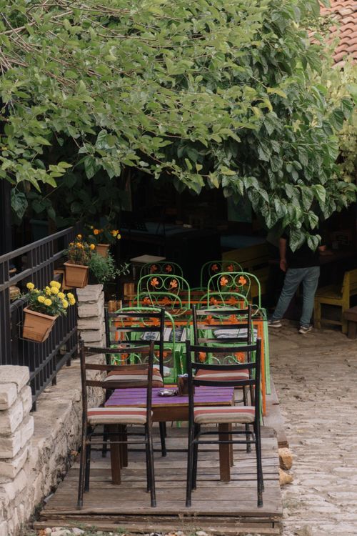 Free Cozy outdoor cafe with colorful chairs and lush greenery. Stock Photo