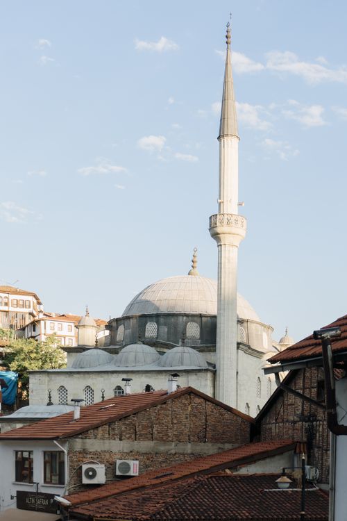Free A picturesque view of a Byzantine mosque with a prominent minaret in a cityscape under a clear sky. Stock Photo