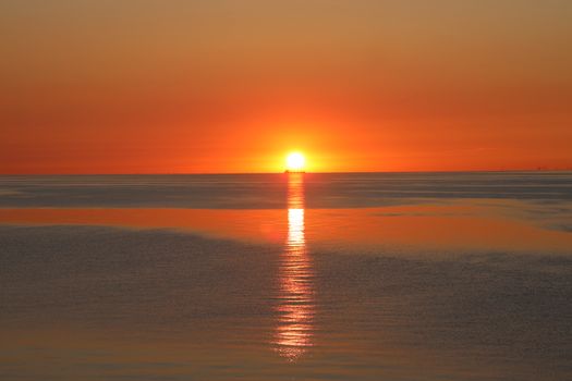 A stunning sunset over the Baltic Sea with a ship silhouette and vibrant colors.