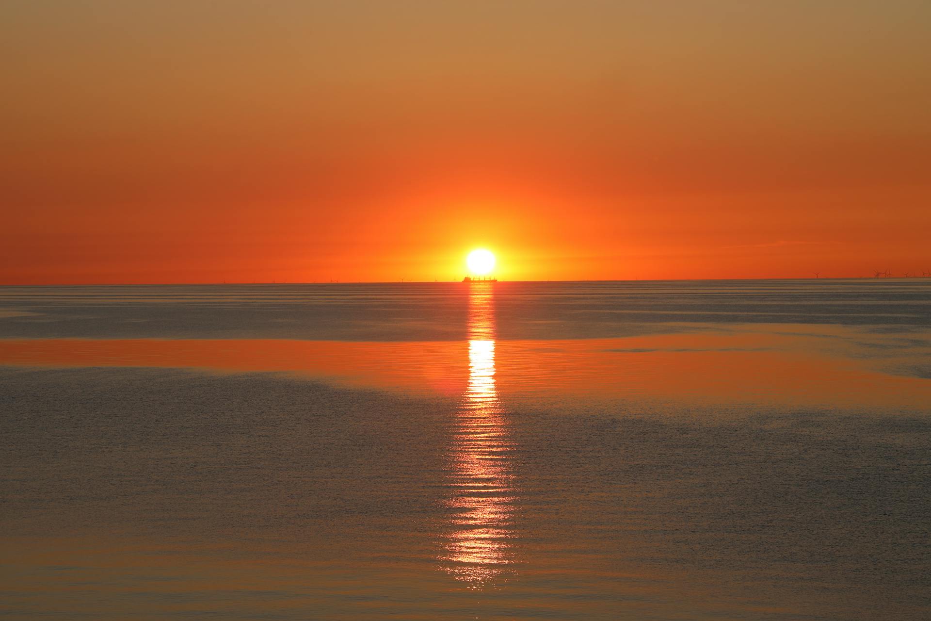 A stunning sunset over the Baltic Sea with a ship silhouette and vibrant colors.
