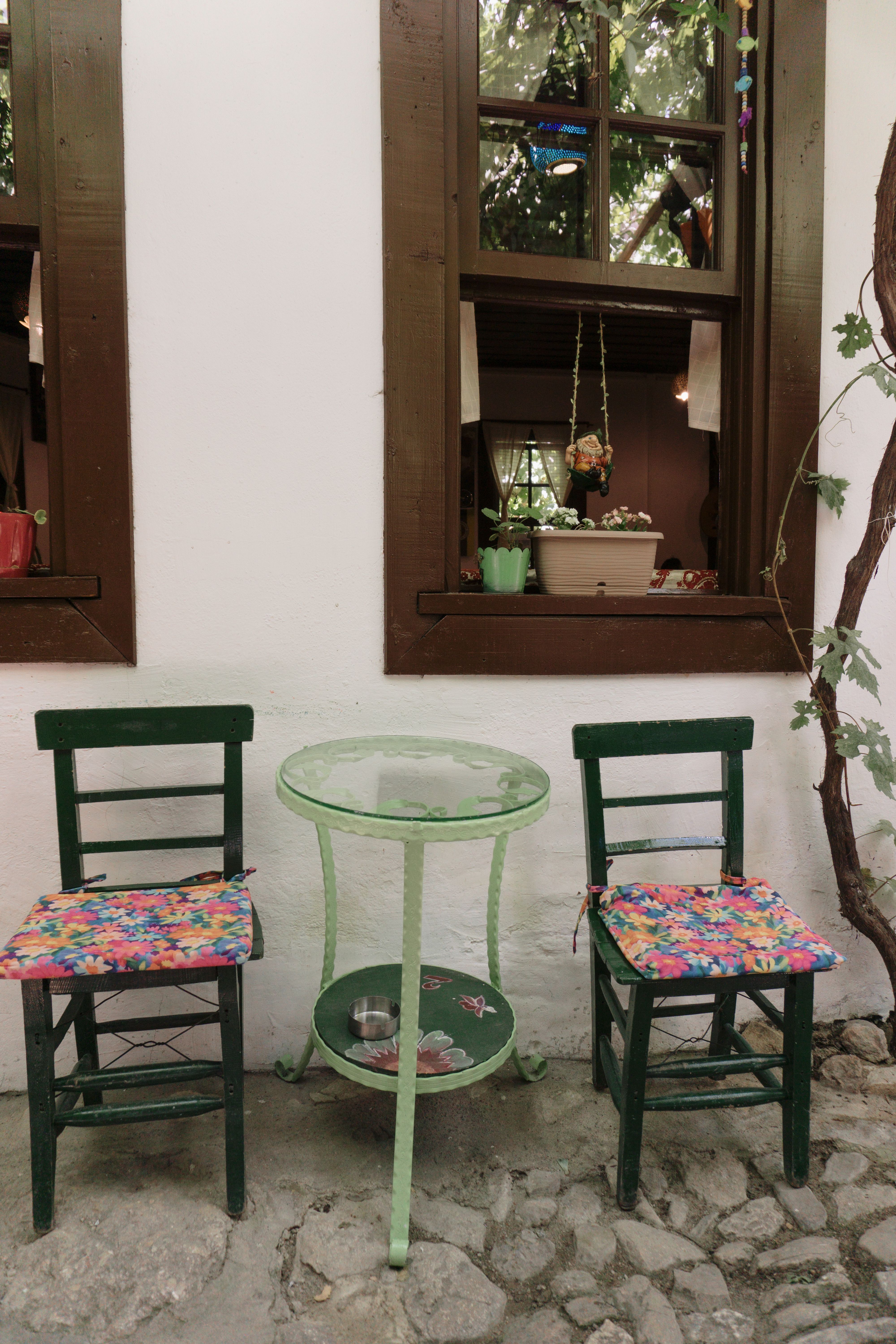 Two green chairs and a table in front of a window · Free Stock Photo