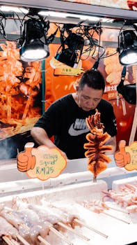 A street vendor cooking sizzling grilled squid at a bustling seafood market.