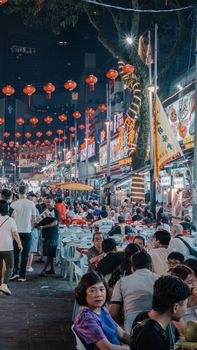 Crowded night market with lanterns and street food vendors, bustling and lively atmosphere.