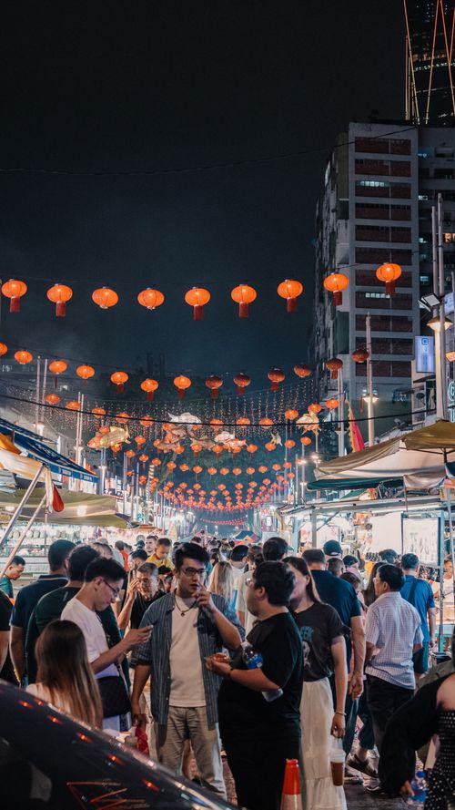 Free Vibrant street scene of a crowded night market with hanging red lanterns. Stock Photo