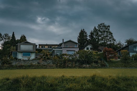 Stylish suburban houses with lush greenery beneath a dramatic cloudy sky, perfect for architecture and landscape themes.