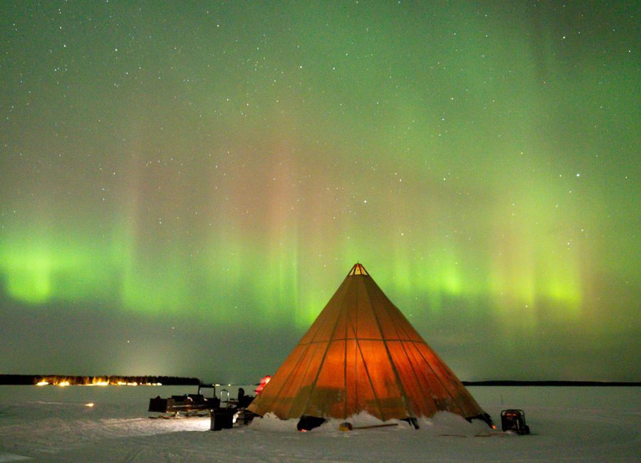 A stunning view of the Northern Lights over a tent in snowy Luleå, Sweden, beautifully captured at night.