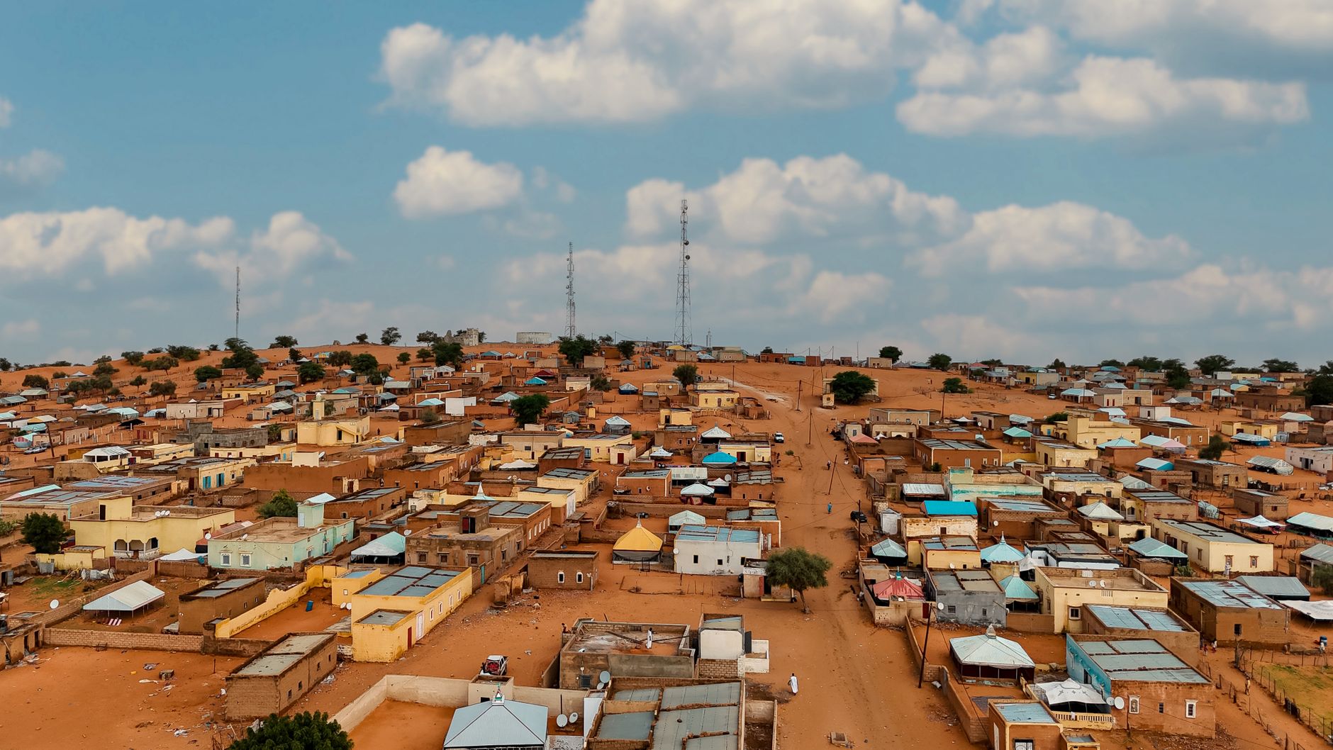Aerial view of a rural desert town in Africa under a bright blue sky with scattered clouds.