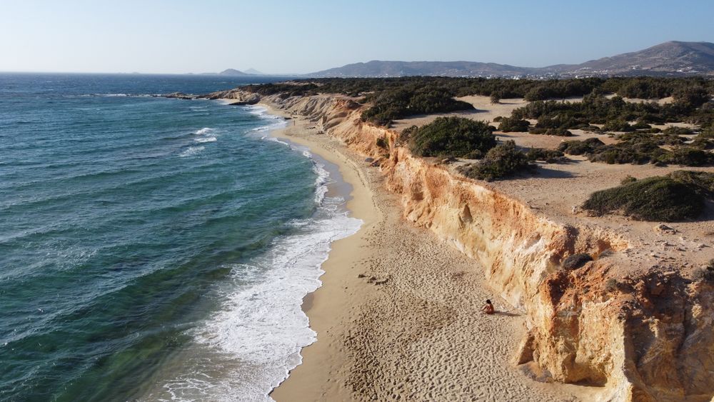 Vista aérea de una playa de Naxos con acantilados y aguas turquesas