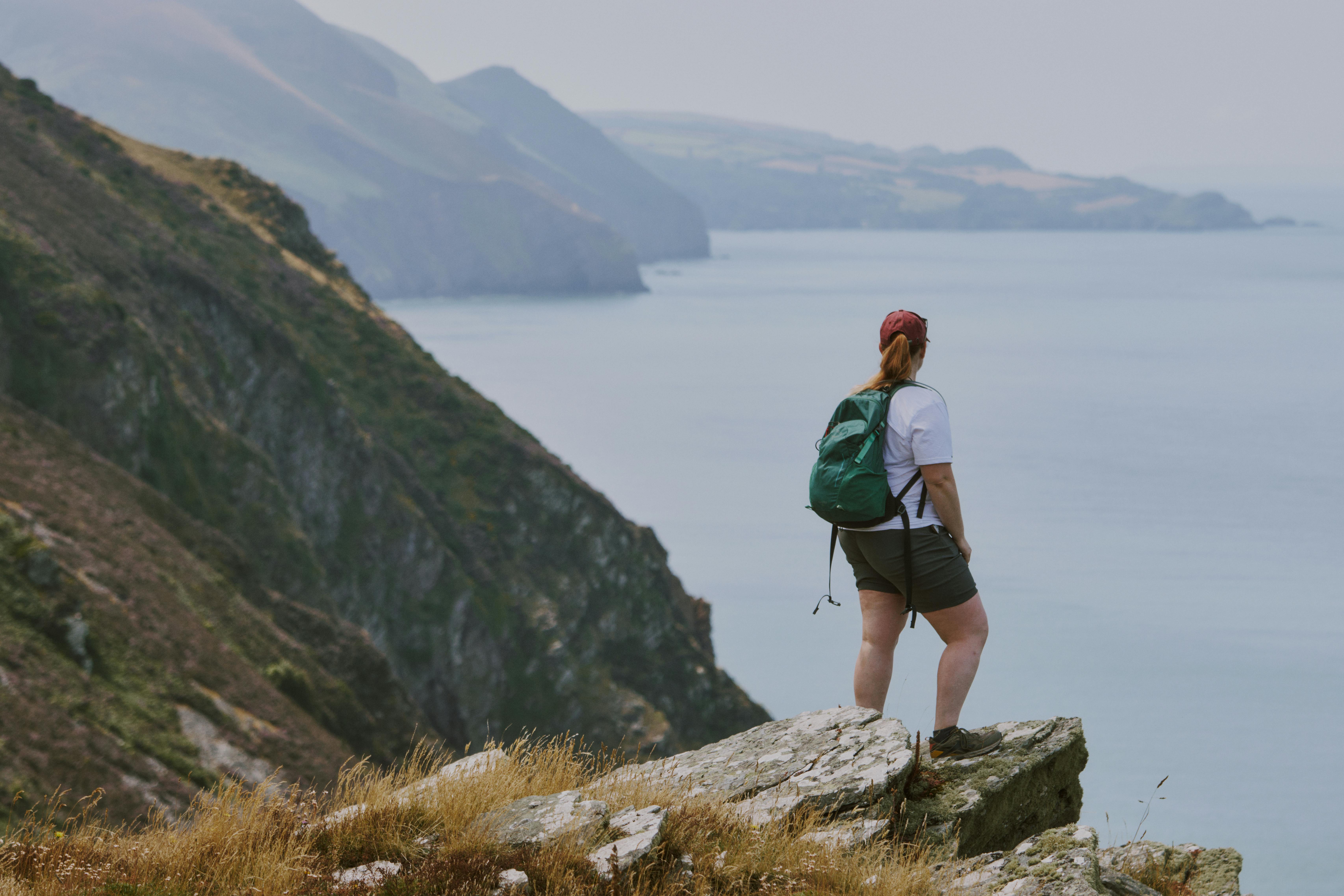 A hiker stands on a cliff overlooking the sea at Lynton, capturing the essence of adventure and exploration.