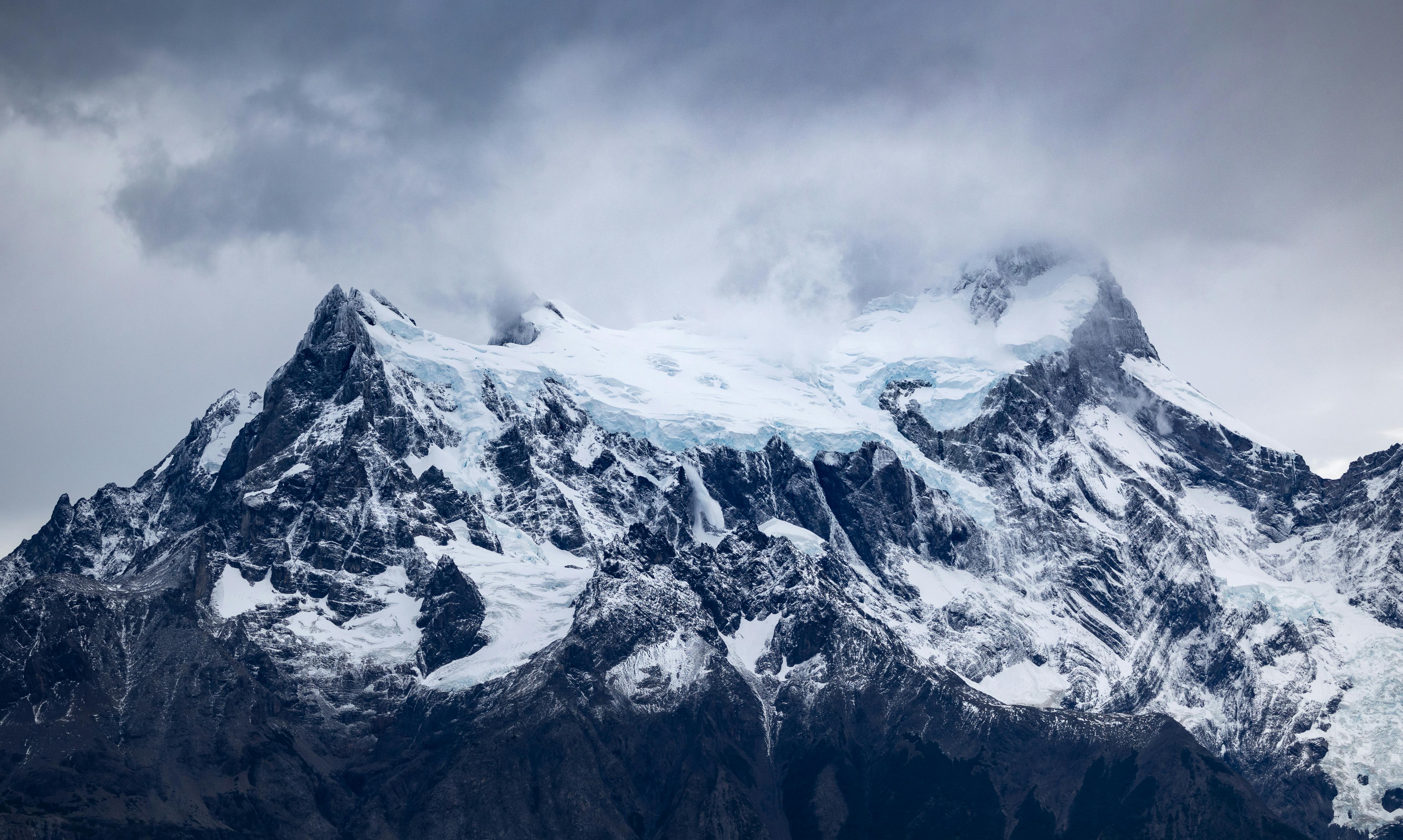 a large mountain covered in snow and clouds