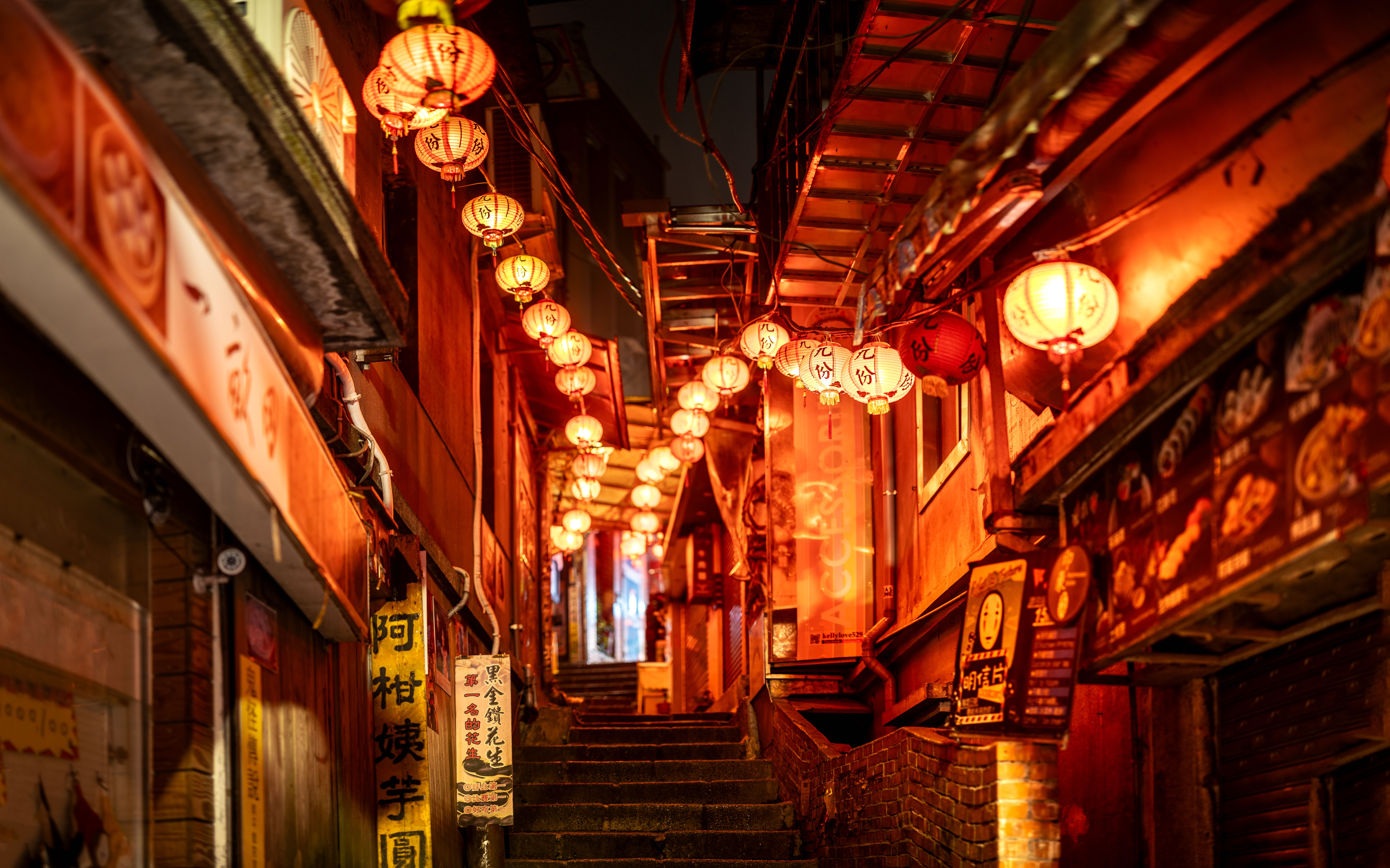 A brightly lit alleyway in Taiwan featuring red lanterns and colorful signs at night.