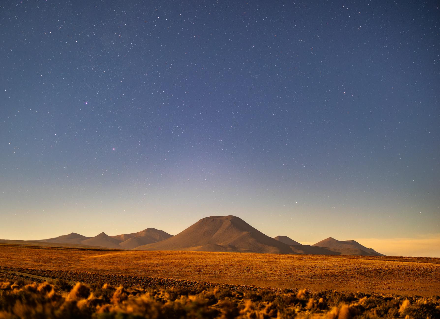 Starry night over a serene desert landscape with distant mountains. Perfect for adventurers and nature lovers.
