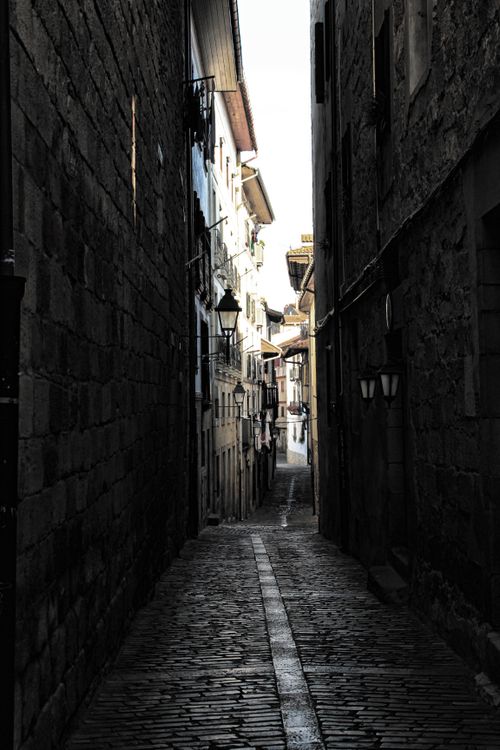 Free Gothic-style narrow alley with cobblestones and shadows in a historic European town Stock Photo
