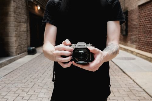 Free Close-up of a photographer with a camera in a brick-lined urban alleyway. Stock Photo