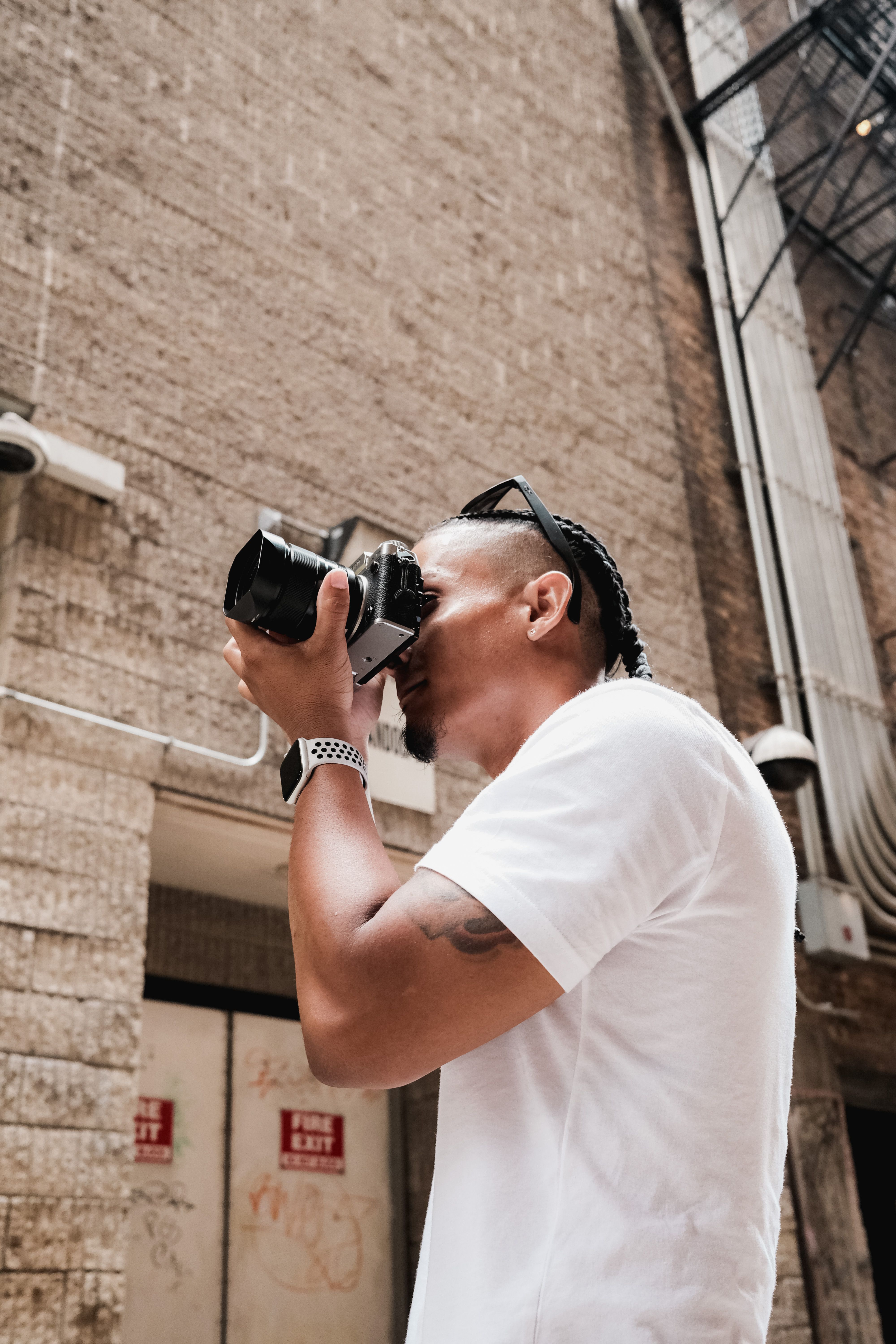 Portrait of a young man photographing city life outdoors with a classic camera.