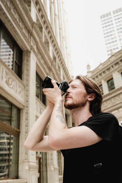 Free A man photographing the cityscape, focusing on urban architecture and design. Stock Photo