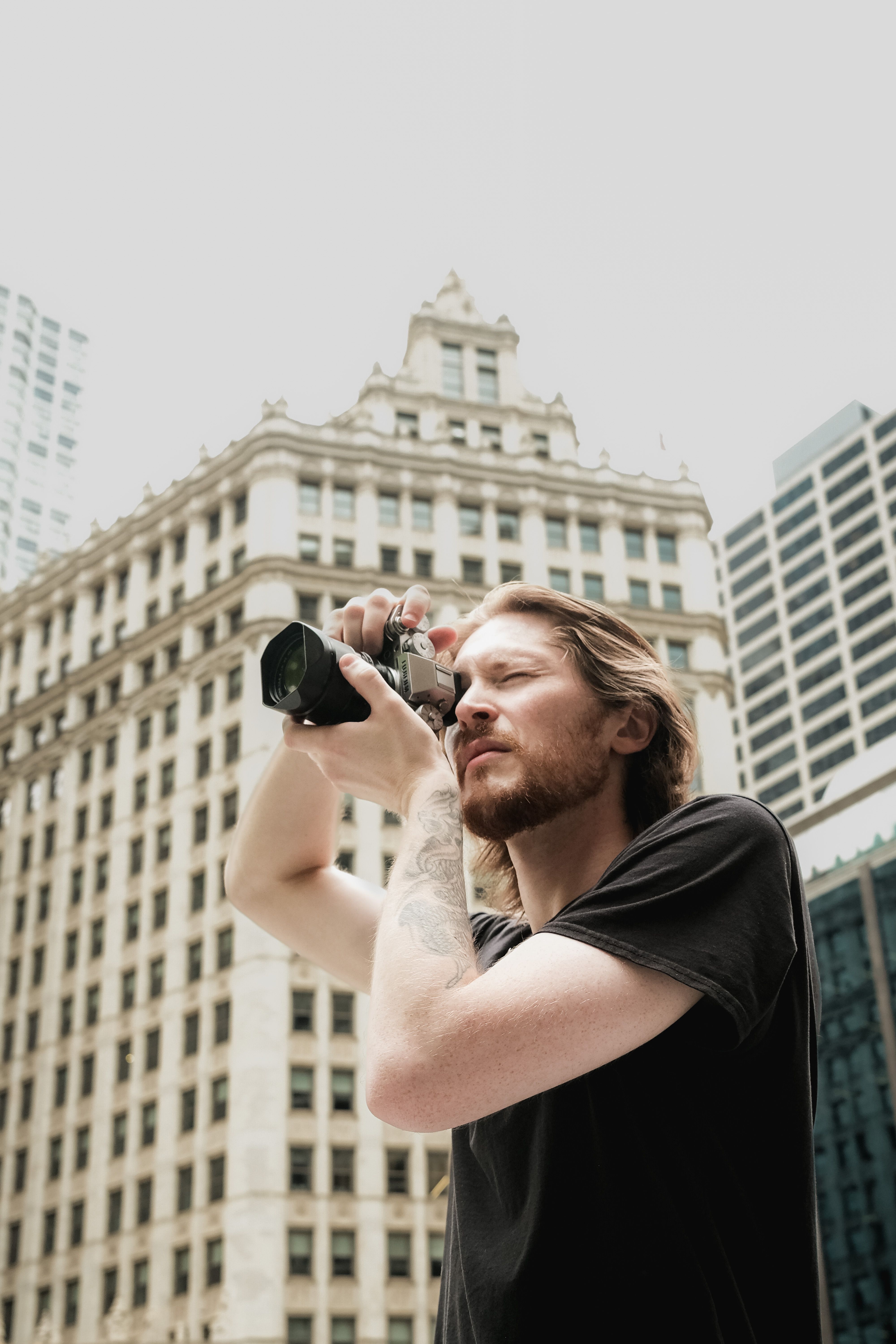 Man taking photos in a busy urban city environment with high-rise buildings in the background.