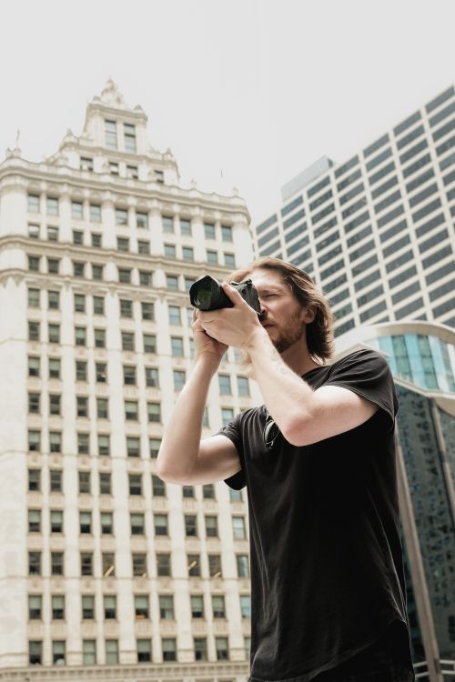 Free Photographer with camera capturing detailed city architecture on a bright day. Stock Photo