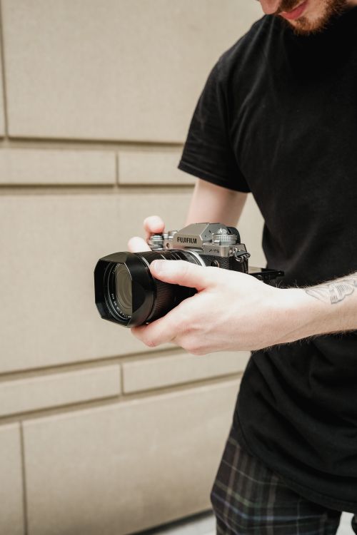 Free Close-up of a person holding a Fujifilm camera outdoors, perfect for photography themes. Stock Photo