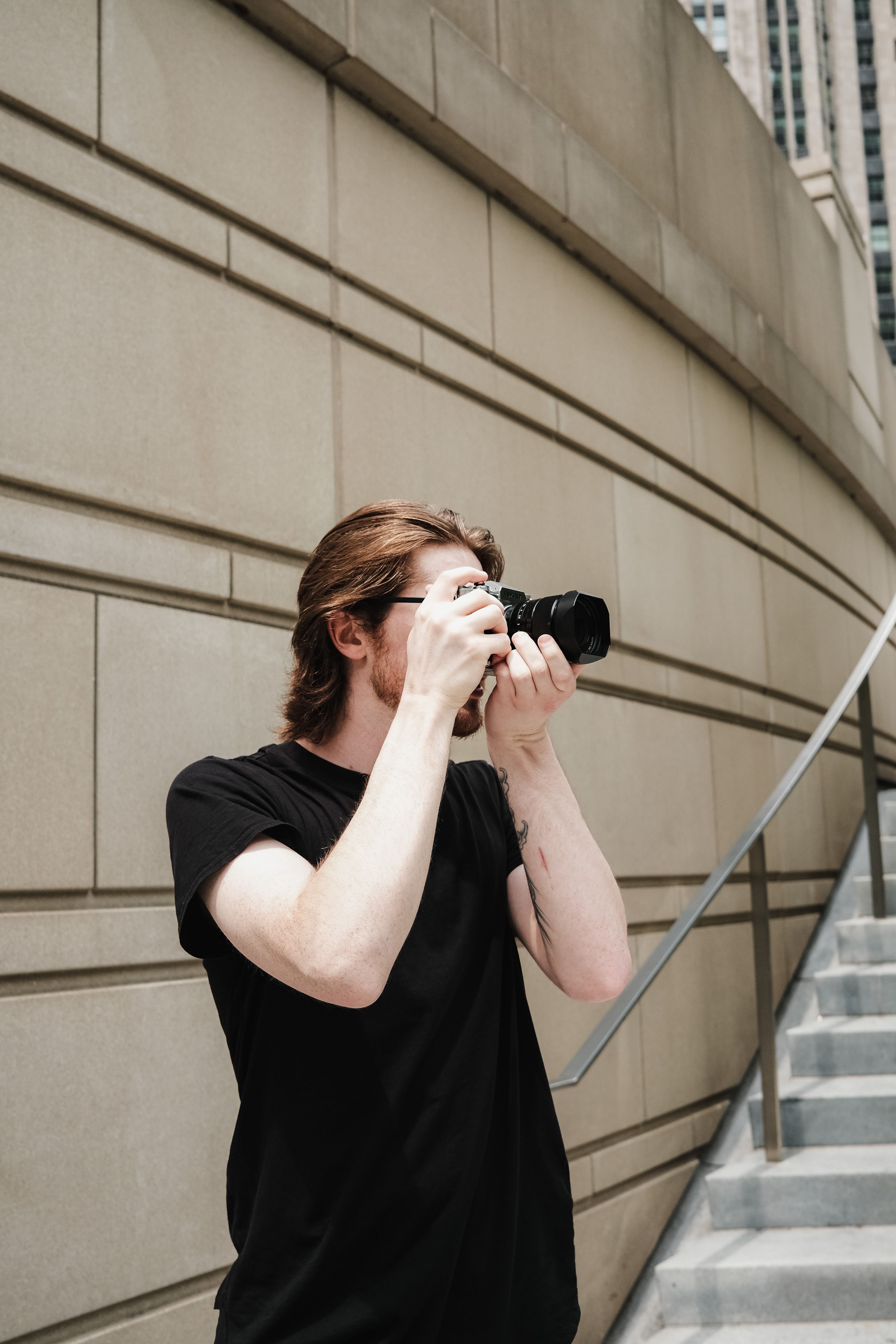 Young man with camera photographing urban setting on stairs.