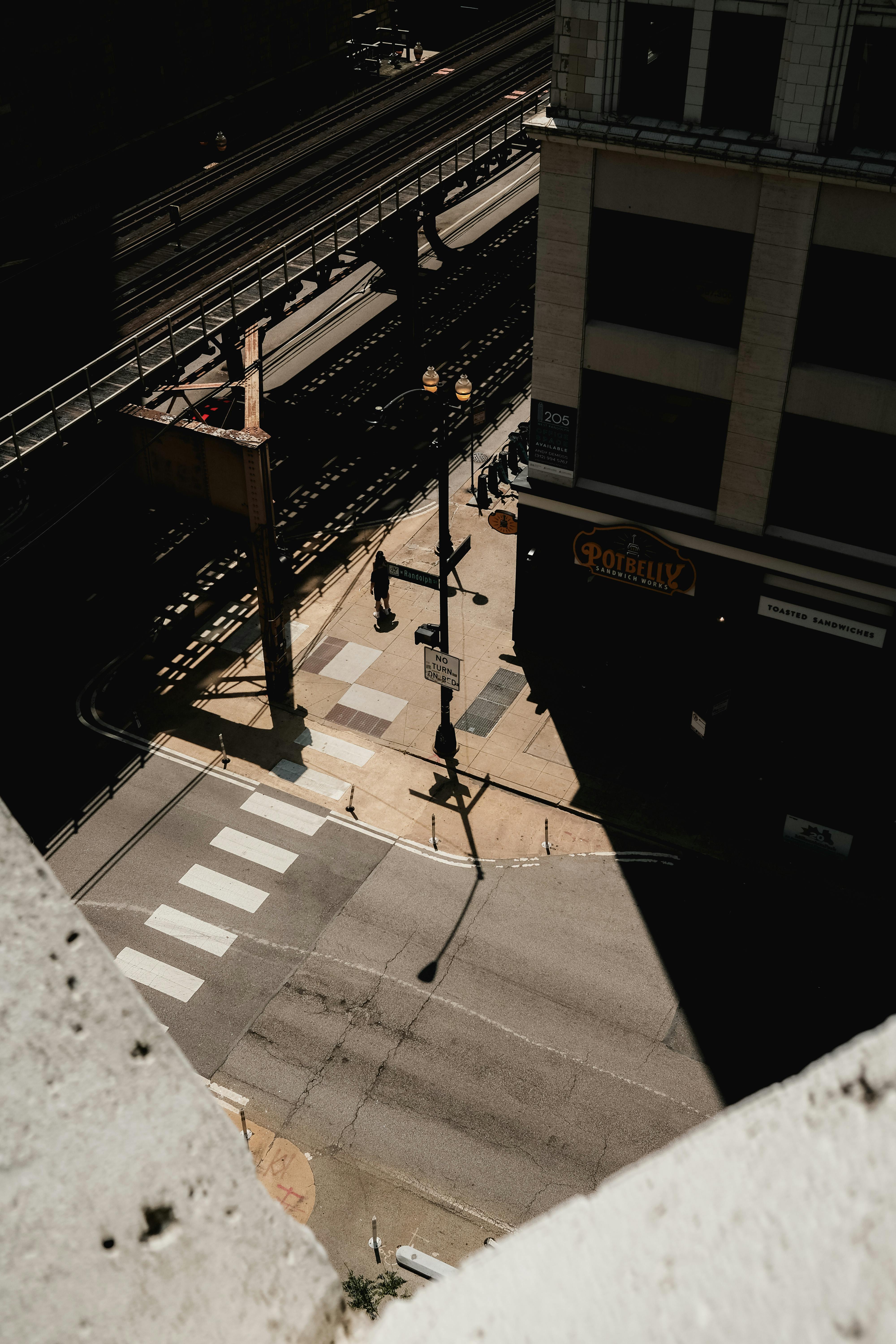 A high-angle view of a Chicago crosswalk and city street with railway shadows.